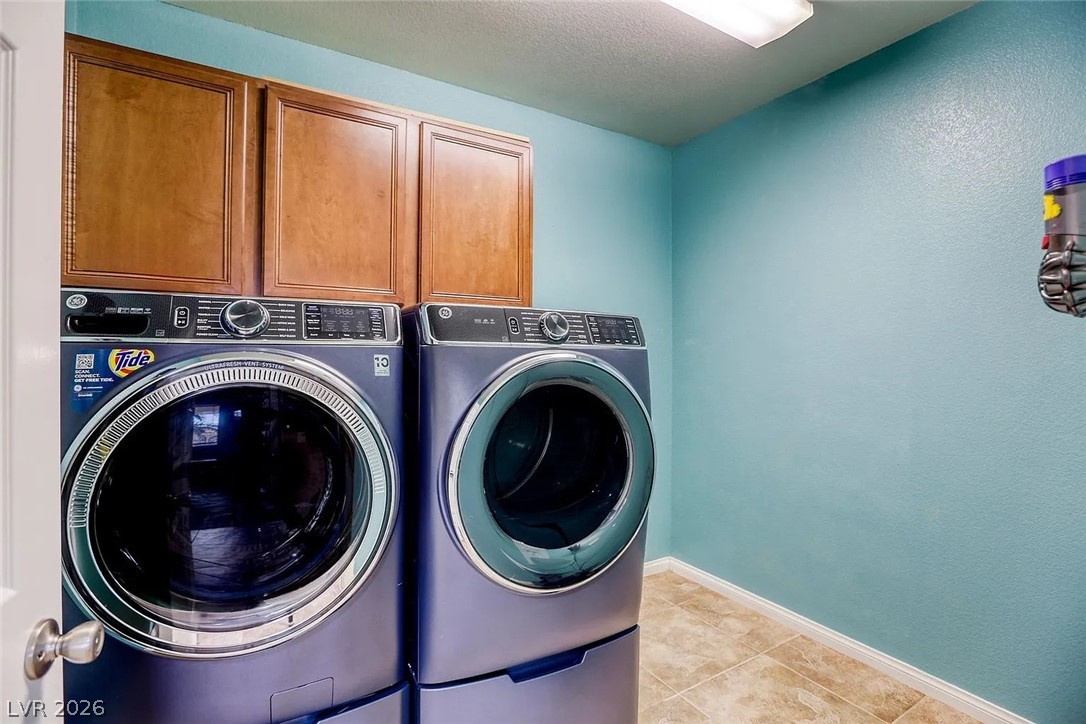692 Blue Crystal Creek Road Henderson, NV 89002 - Photo 12 of 29 Laundry room with cabinet space, a textured ceiling, washer and clothes dryer, light tile patterned flooring, and a textured wall