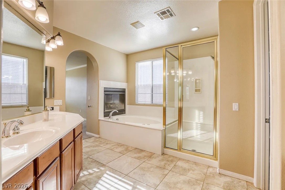 692 Blue Crystal Creek Road Henderson, NV 89002 - Photo 16 of 29 Full bathroom featuring a stall shower, a garden tub, vanity, a textured ceiling, and light tile patterned flooring