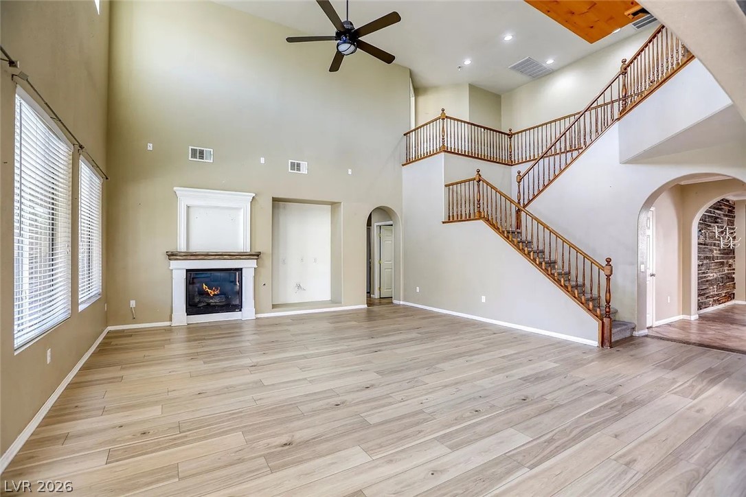 692 Blue Crystal Creek Road Henderson, NV 89002 - Photo 19 of 29 Unfurnished living room with arched walkways, ceiling fan, a glass covered fireplace, light wood-type flooring, and recessed lighting