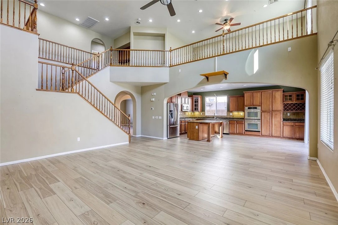 692 Blue Crystal Creek Road Henderson, NV 89002 - Photo 8 of 29 Unfurnished living room with arched walkways, recessed lighting, ceiling fan, light wood-style flooring, and a high ceiling