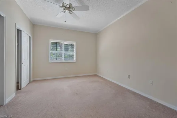 an empty room with a chandelier fan and windows
