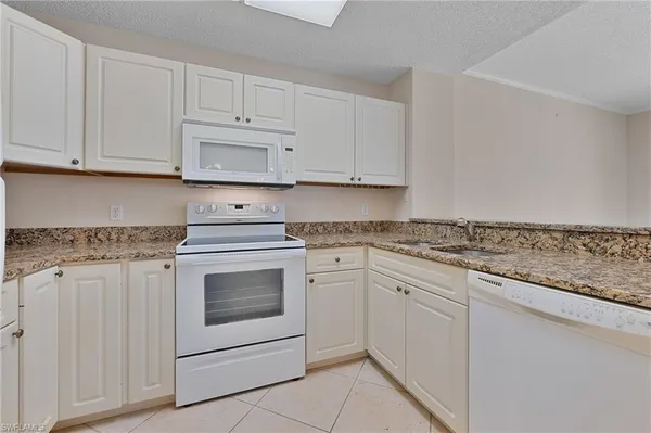 a kitchen with granite countertop white cabinets and white appliances