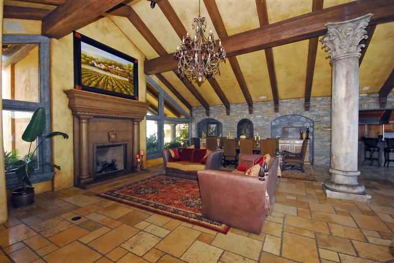 4678 Millerton Road Friant, CA 93626 - Photo 17 of 86 The Great Room ~ This seating area takes full advantage of the over-sized stone fireplace and crowned with an old world chandelier. Beyond this seating area is the Formal Dining Area and stacked stone wall with two furniture alcoves and a temperature controlled wine vault with iron & glass door.
