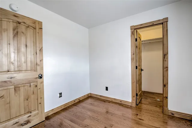 an empty room with wooden floor and closet area