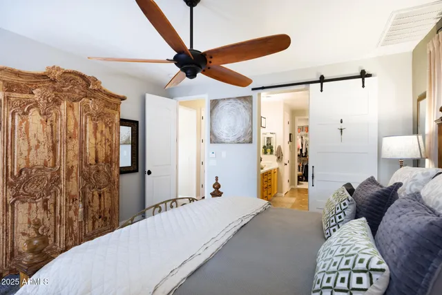 a spacious bedroom with a bed a couch and a chandelier
