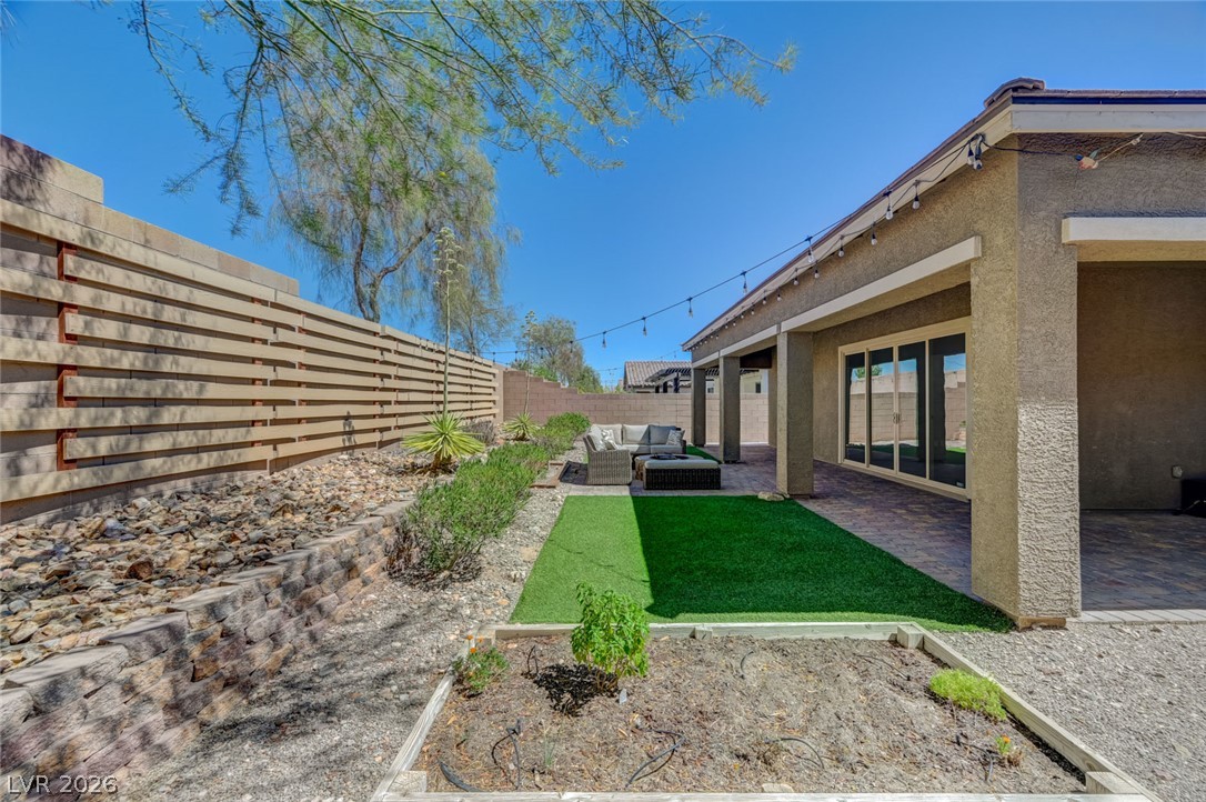 8197 Riley Love Street Las Vegas, NV 89139 - Photo 41 of 48 A well-appointed yard boasts a covered patio, artificial turf, and a charming garden bed.
