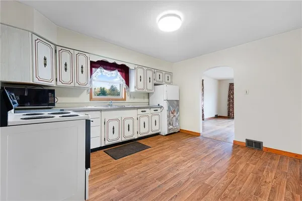 a kitchen with stainless steel appliances granite countertop a stove a sink and a microwave oven on the wooden floor