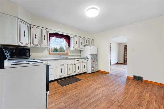 a kitchen with stainless steel appliances granite countertop a stove a sink and a microwave oven on the wooden floor