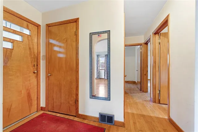 a view of an empty room with wooden floor and fan