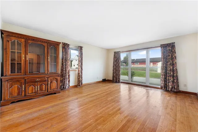a view of an empty room with window and wooden floor
