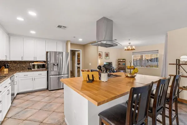 a kitchen with stainless steel appliances kitchen island granite countertop a dining table chairs and refrigerator