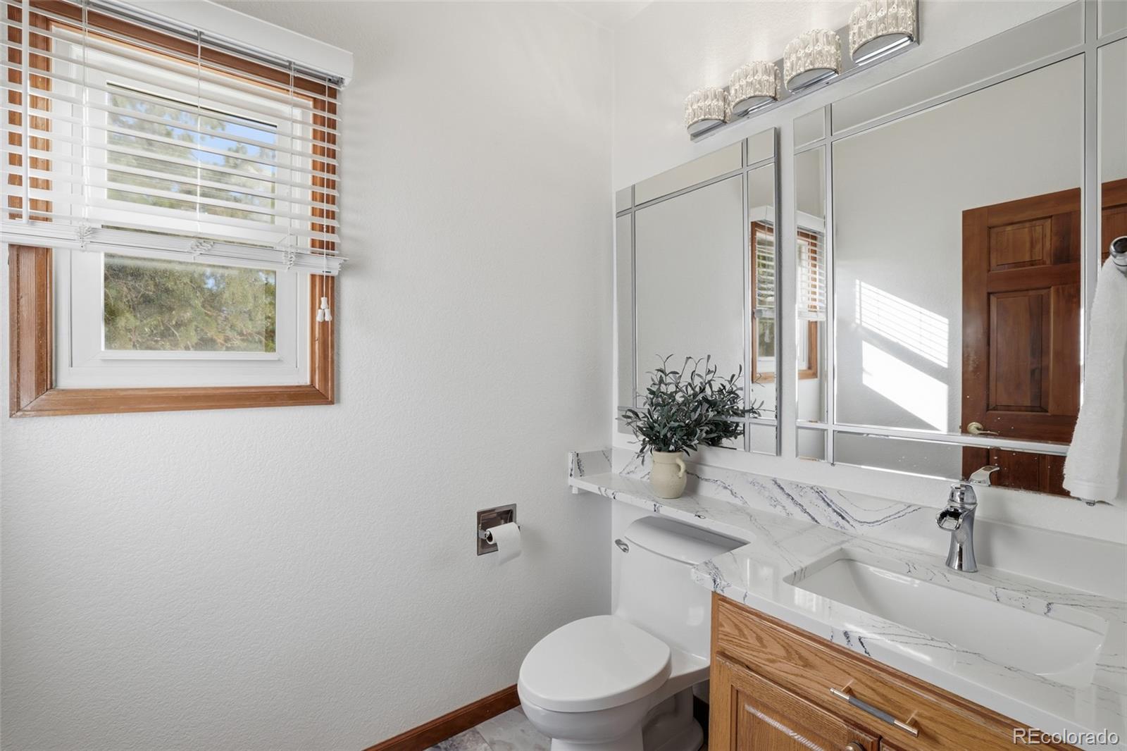10917 Ammons Street Broomfield, CO 80021 - Photo 19 of 47 a bathroom with a granite countertop toilet a sink and a mirror