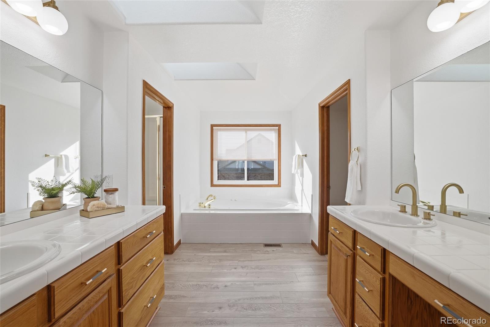 10917 Ammons Street Broomfield, CO 80021 - Photo 24 of 47 a bathroom with a granite countertop sink mirror and a bathtub