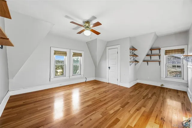 a view of empty room with wooden floor and fan