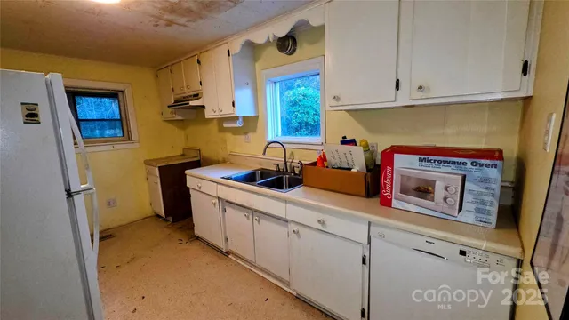a utility room with stainless steel appliances white cabinets and a window
