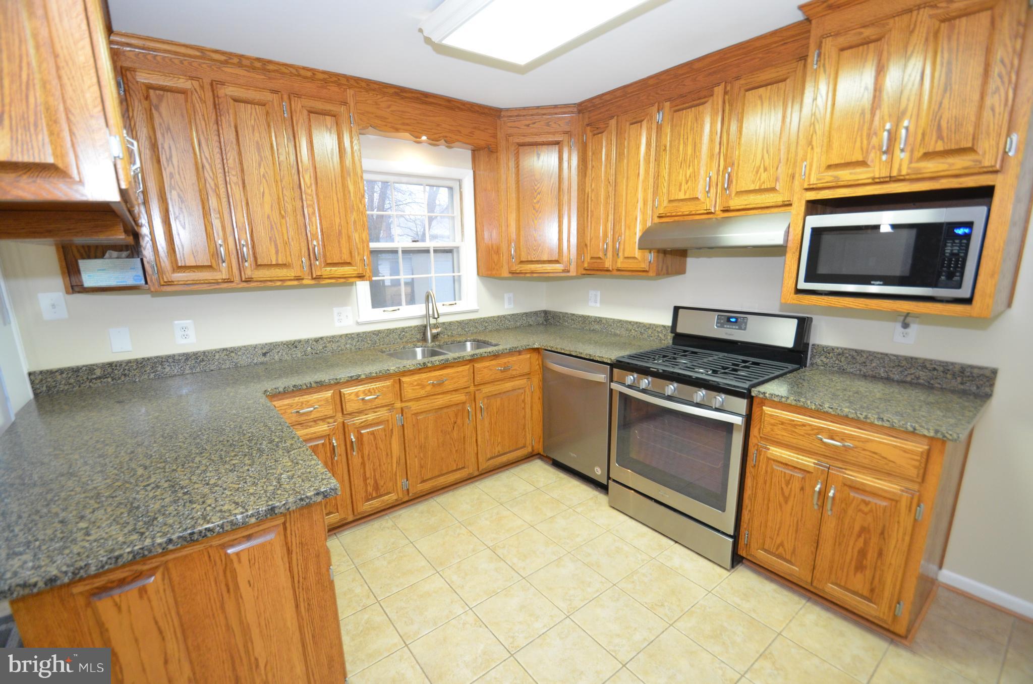 5612 Ashfield Road Alexandria, VA 22315 - Photo 9 of 29 a kitchen with stainless steel appliances granite countertop a stove a sink and a microwave