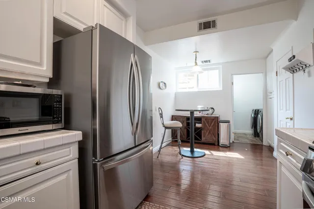 a kitchen with a refrigerator a stove and a dining table with wooden floor