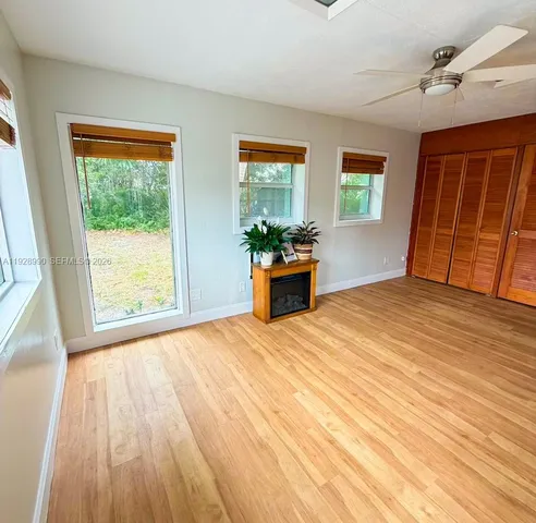 a view of empty room with wooden floor and fan