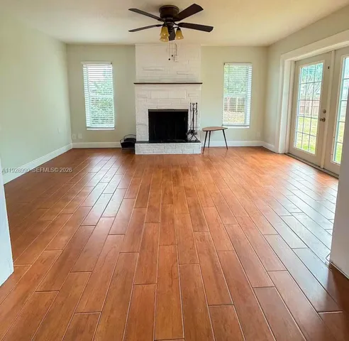 wooden floor fireplace and windows in an empty room