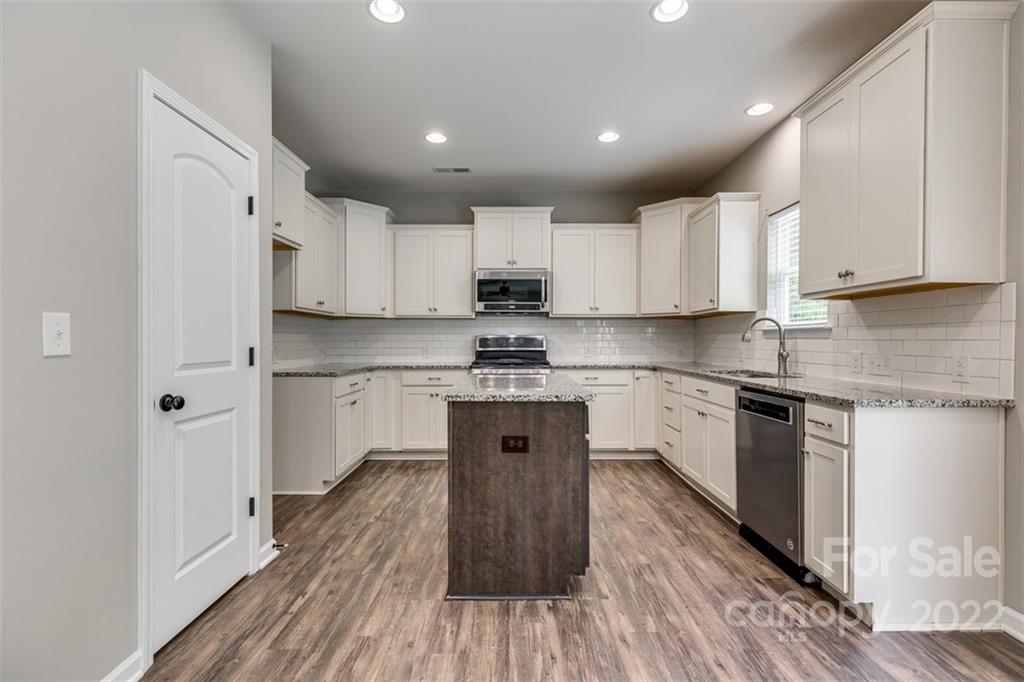 6403 Bluegill Road Charlotte, NC 28216 - Photo 12 of 48 a kitchen with stainless steel appliances white cabinets sink and wooden floor