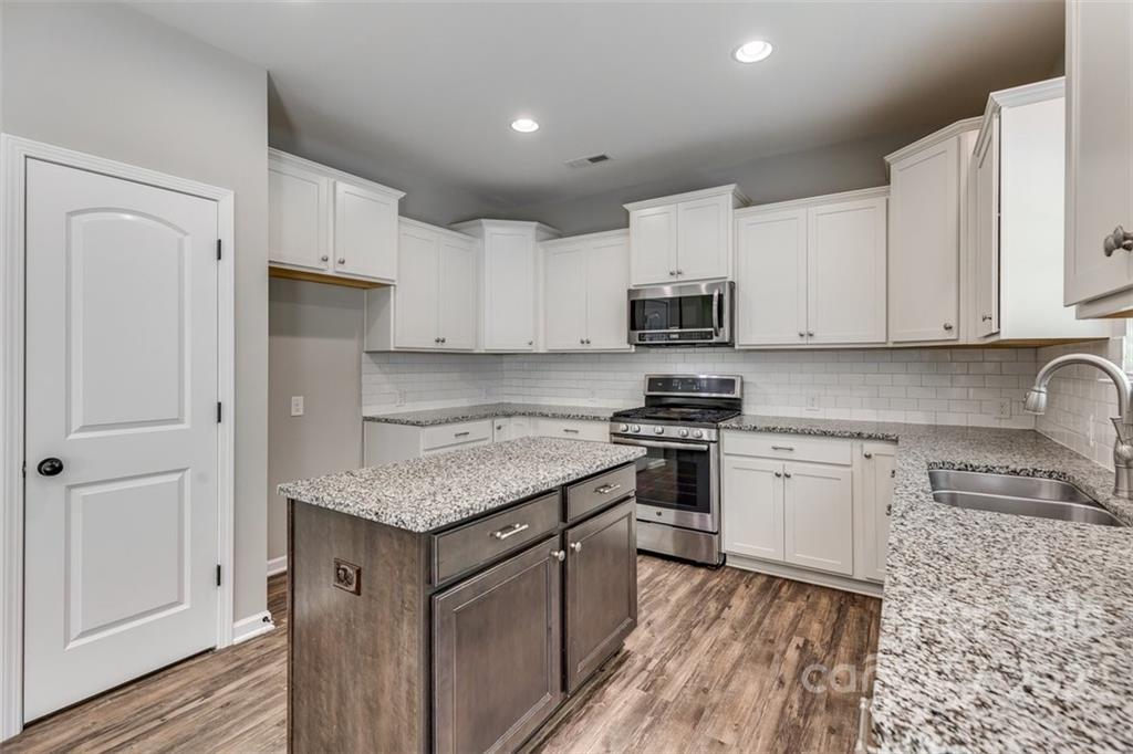 6403 Bluegill Road Charlotte, NC 28216 - Photo 14 of 48 a kitchen with stainless steel appliances granite countertop a stove top oven a sink dishwasher and a refrigerator with wooden cabinets
