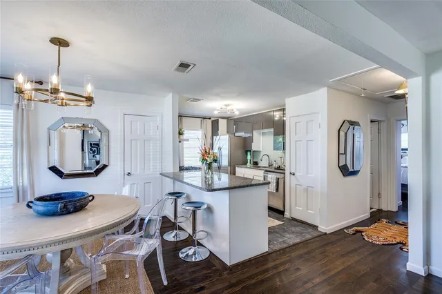 a kitchen with stainless steel appliances kitchen island granite countertop a table chairs in it and wooden floors