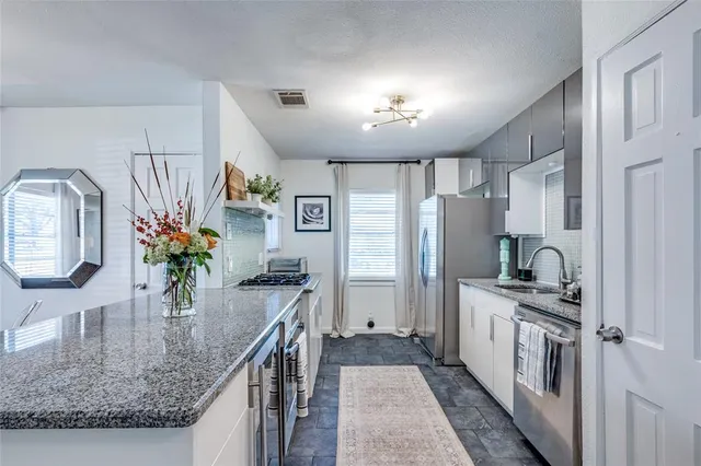 a kitchen with stainless steel appliances granite countertop a sink stove and refrigerator