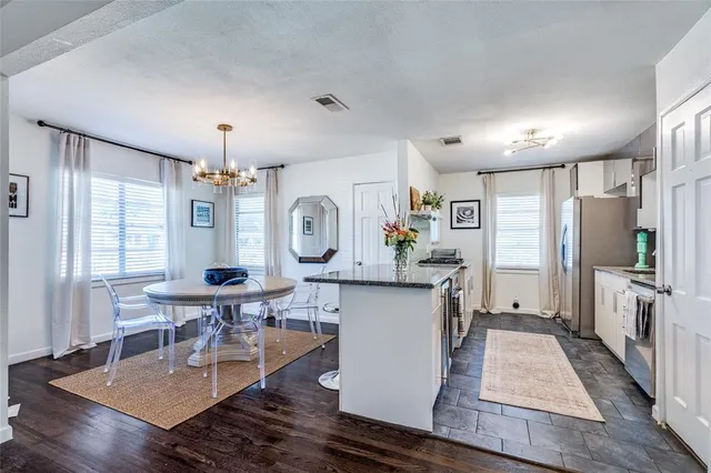 a kitchen with stainless steel appliances granite countertop a refrigerator a sink a stove and white cabinets