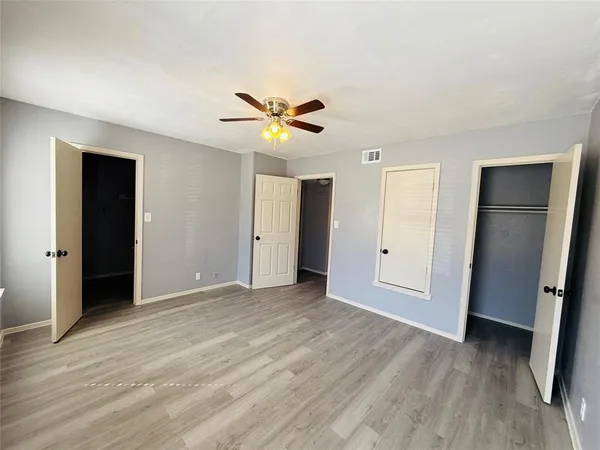 an empty room with wooden floor and ceiling fan