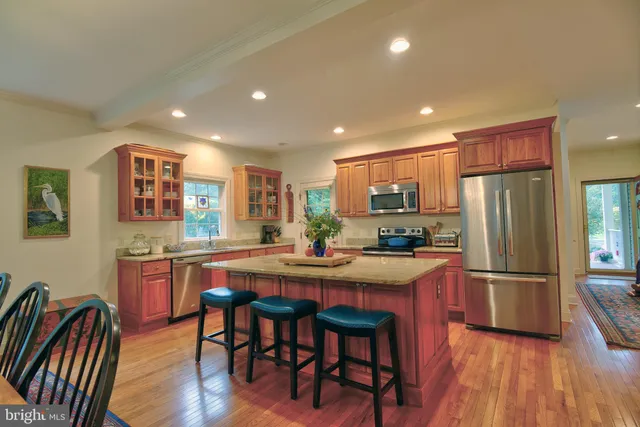 a kitchen with stainless steel appliances granite countertop a refrigerator a stove a sink a dining table and chairs