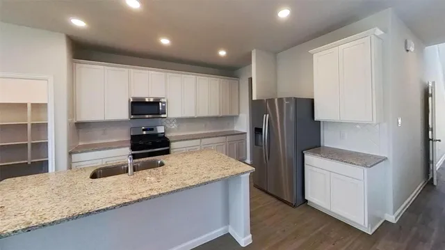 a kitchen with granite countertop a refrigerator stove and sink