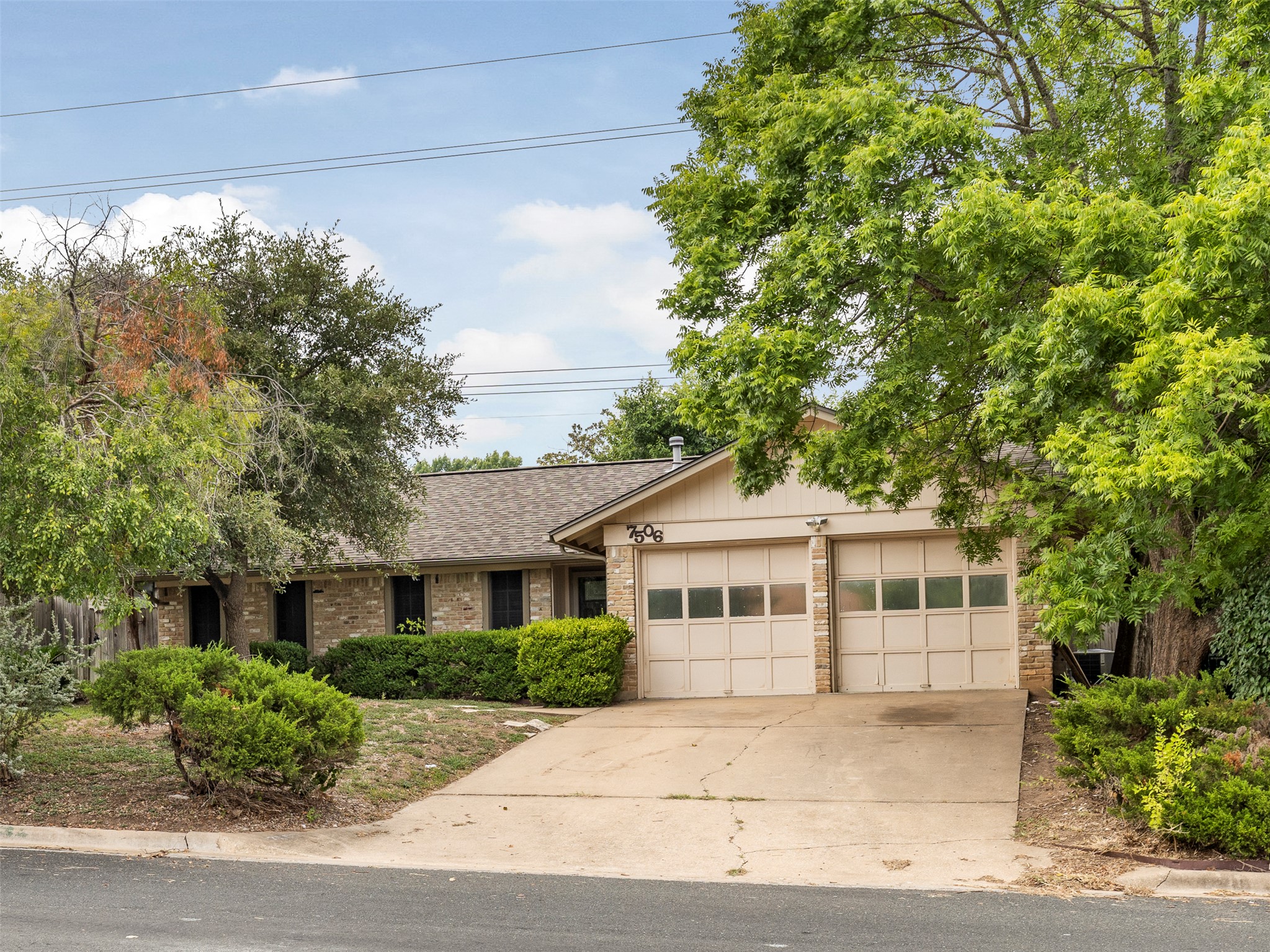 7506 Glenhill Road Austin, TX 78752 - Photo 1 of 24 Mature trees and landscaping frame this inviting brick facade with an attached two-car garage.