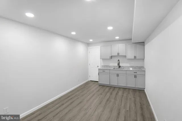 a kitchen with granite countertop a sink cabinets and wooden floor