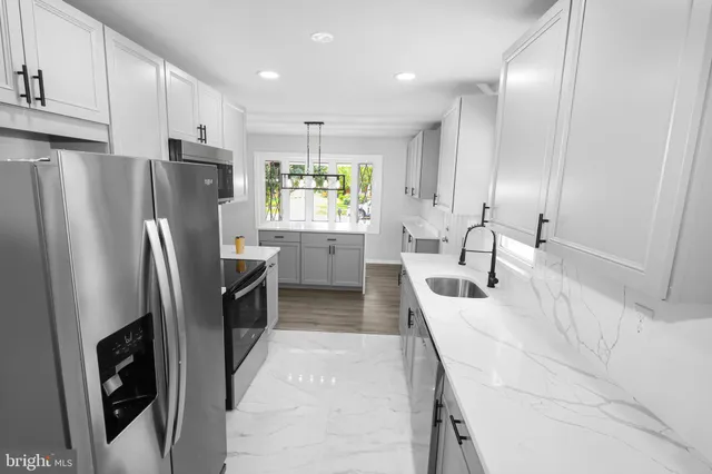 a kitchen with stainless steel appliances granite countertop a refrigerator a sink a stove and a refrigerator with wooden floor