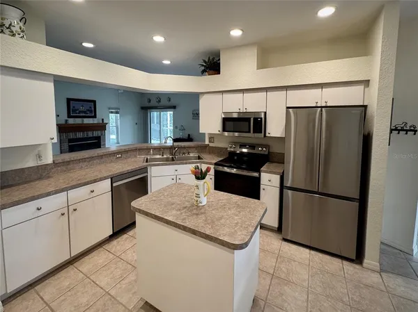 a kitchen with stainless steel appliances granite countertop a refrigerator a stove a sink and a microwave