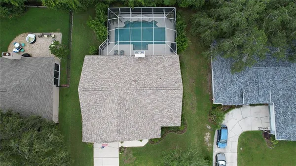 an aerial view of a house with a yard and trees all around