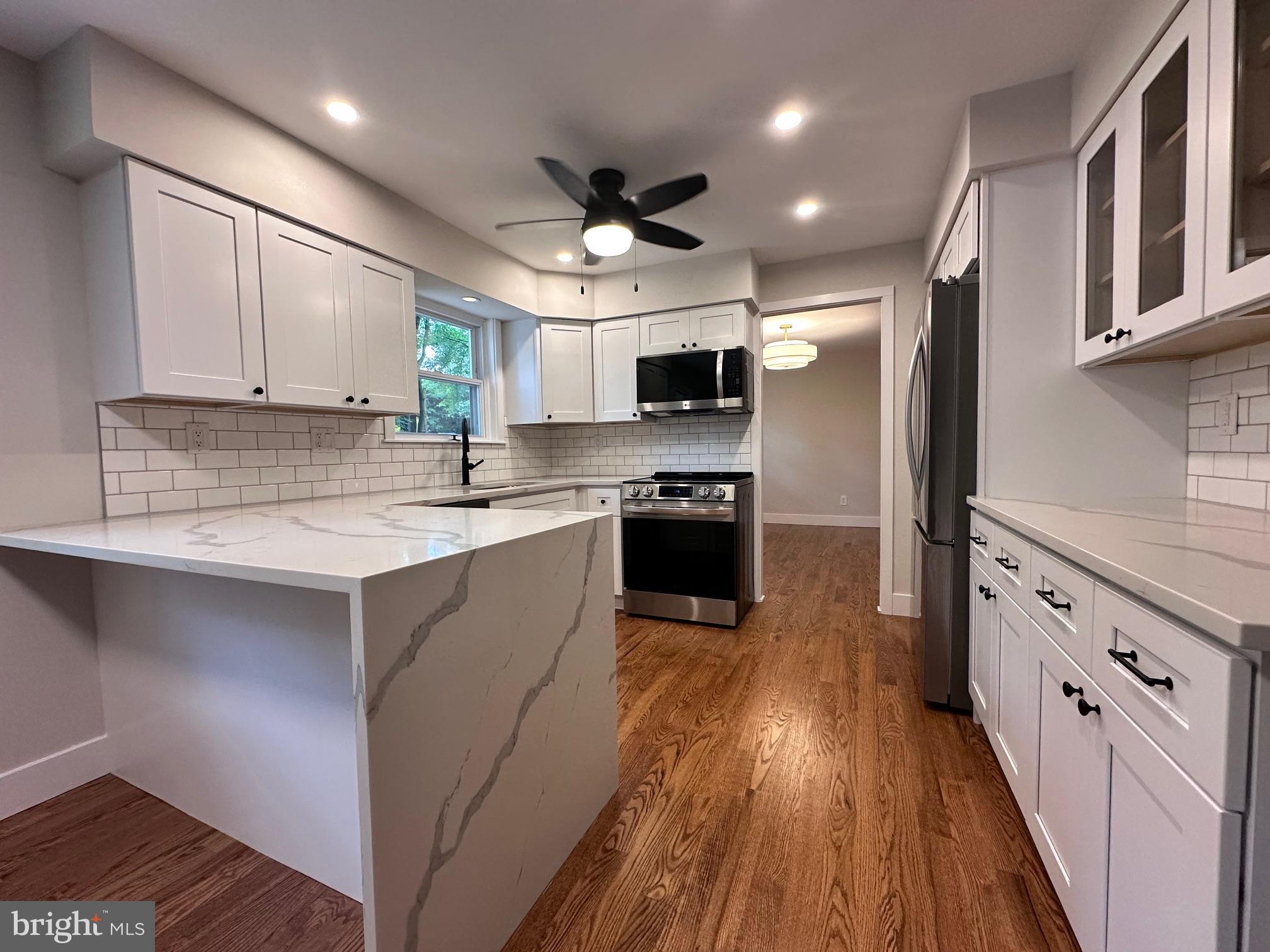 215 Bridge Road Upper Chichester, PA 19061 - Photo 14 of 35 a kitchen with stainless steel appliances granite countertop a sink a stove top oven a refrigerator cabinets and wooden floor