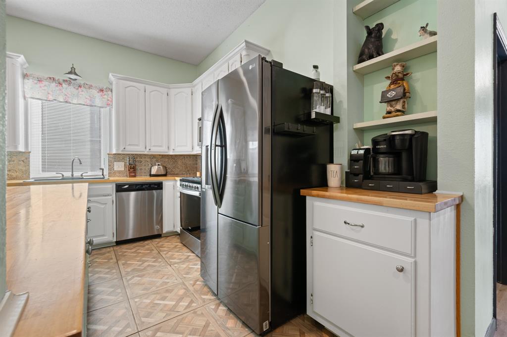 905 Evandale Road Burleson, TX 76028 - Photo 12 of 40 a kitchen with a refrigerator sink and cabinets