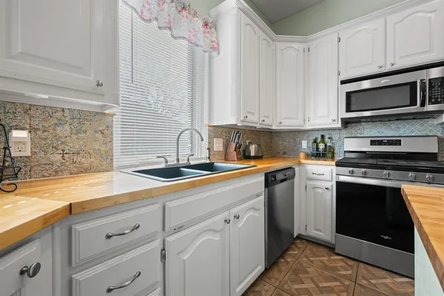 a kitchen with stainless steel appliances granite countertop a sink a stove and a microwave