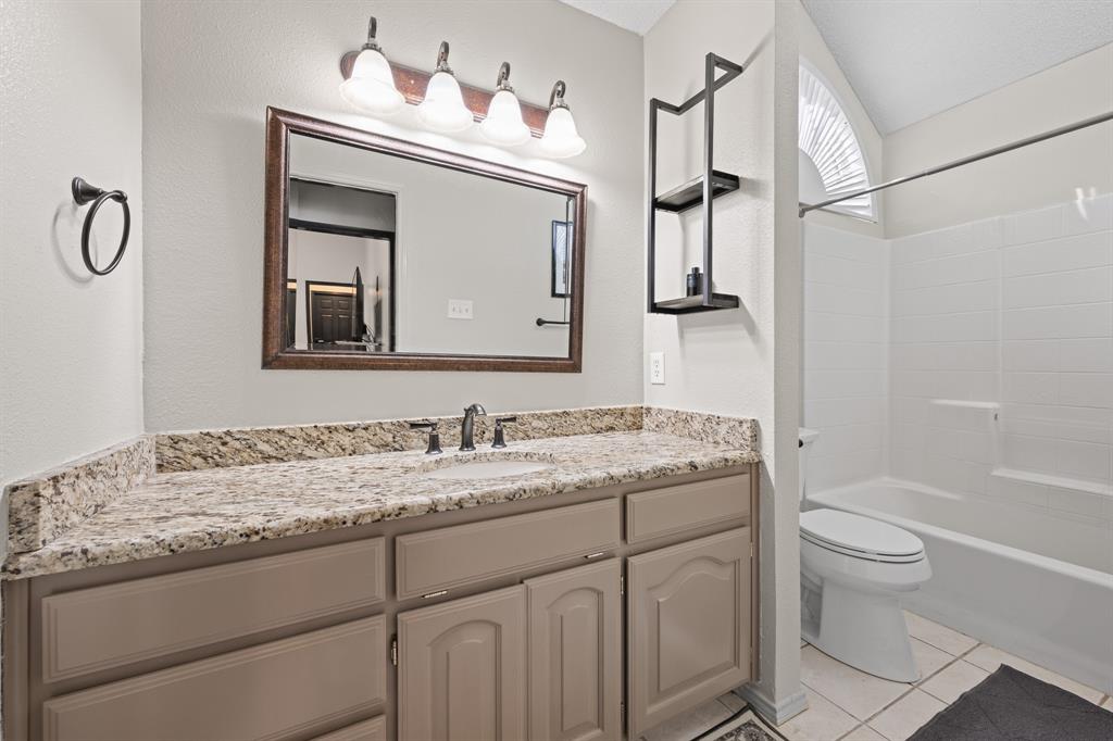 905 Evandale Road Burleson, TX 76028 - Photo 24 of 40 a bathroom with a granite countertop sink a toilet and a mirror