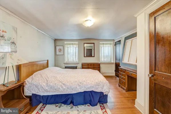 a bedroom with a bed and a dresser with wooden floor