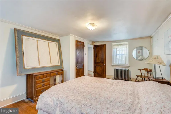 a bedroom with a bed and dresser with wooden floor