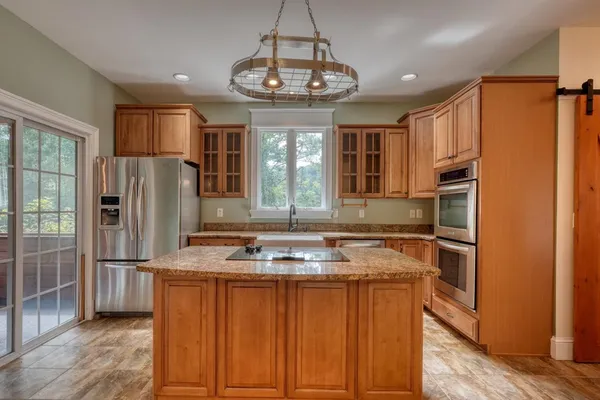 a kitchen with stainless steel appliances granite countertop a refrigerator a stove and a sink with wooden floor