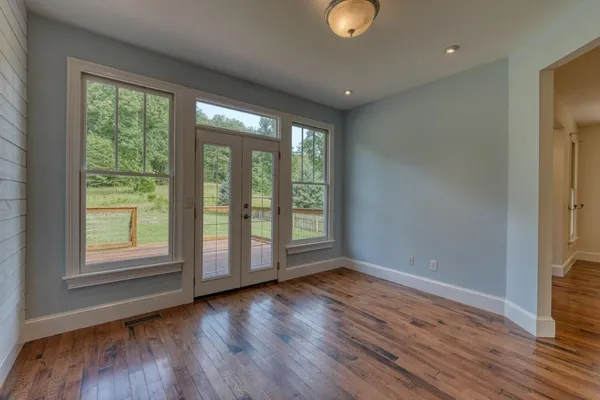 an empty room with wooden floor and windows