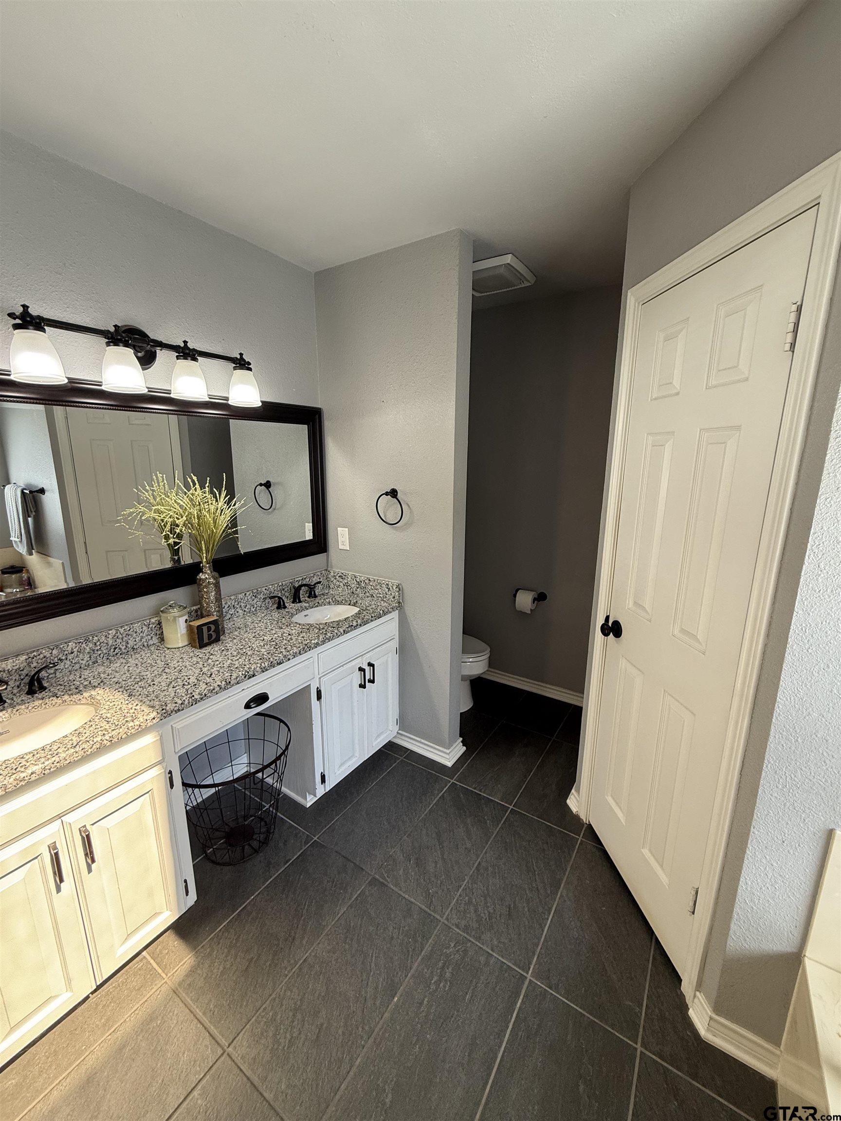 3207 McDonald Road Tyler, TX 75701 - Photo 12 of 24 a bathroom with a double vanity sink and mirror