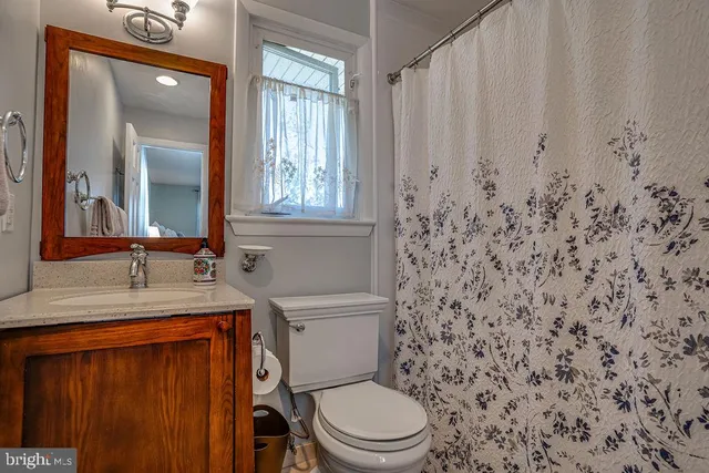 a bathroom with a granite countertop toilet sink and mirror
