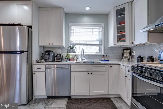 a kitchen with stainless steel appliances white cabinets and a refrigerator