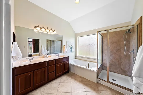 a bathroom with a double vanity sink mirror and bathtub
