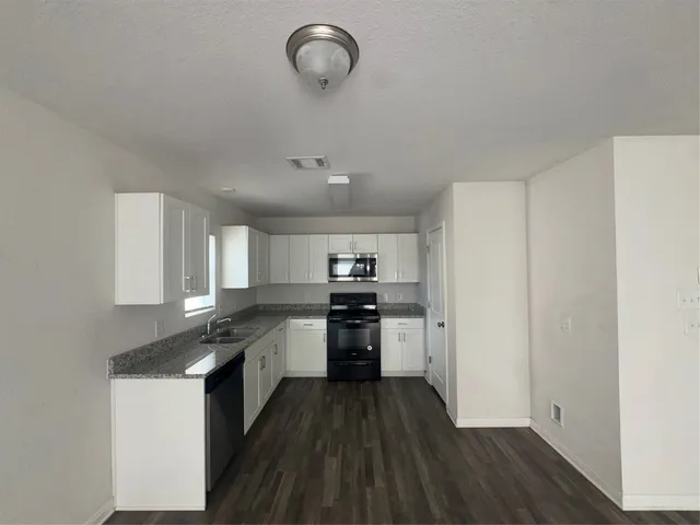 a kitchen with a refrigerator a stove top oven and wooden floor