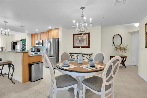a dining room with furniture a chandelier and kitchen view